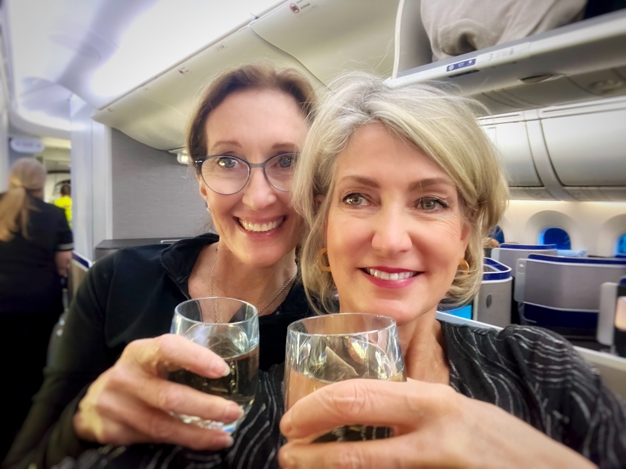 Two women enjoying a glass of wine in first class